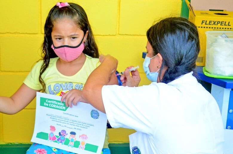 Pequena valente: garotinha durante a vacinação exibe, orgulhosa, o Certificado da Coragem - Crédito: Divulgação