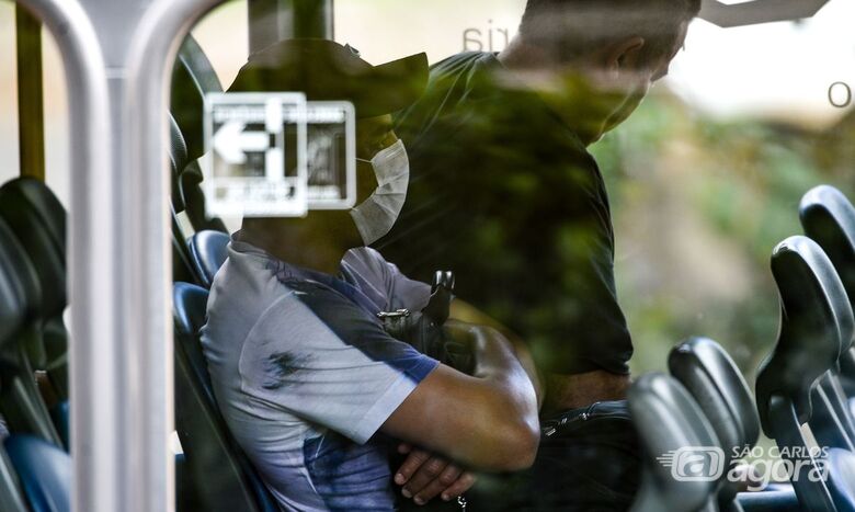 Homem usa máscara de proteção facial em ônibus - Crédito: © Marcello Casal JrAgência Brasil