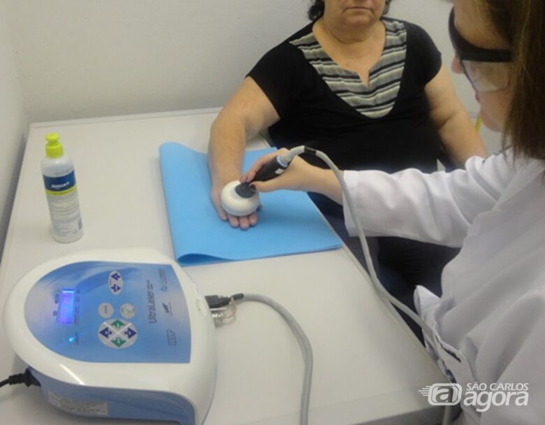 Foto durante um atendimento com pessoa idosa utilizando o dispositivo que associa laser e ultrassom para tratamento de osteoartrite nas mãos. - Crédito: arquivo pessoal