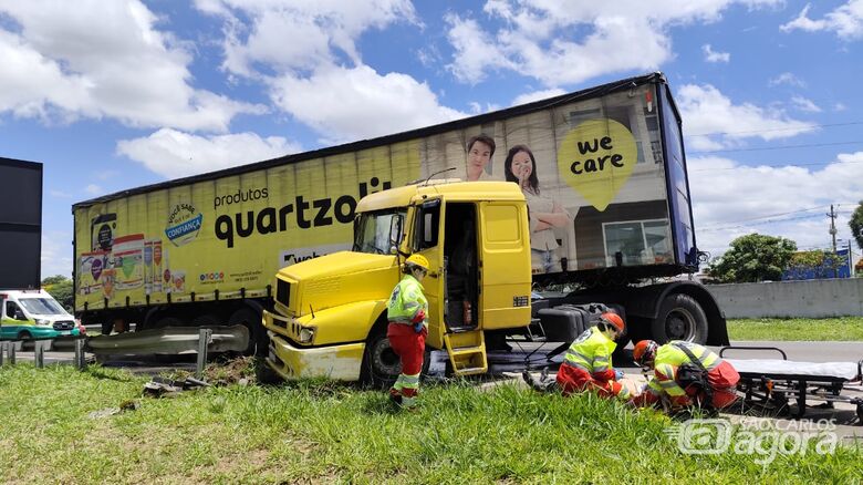 Caminhoneiro é atendido por socorristas; à esquerda, carreta ficou em "L" após colidir em guardrail - Crédito: Maycon Maximino