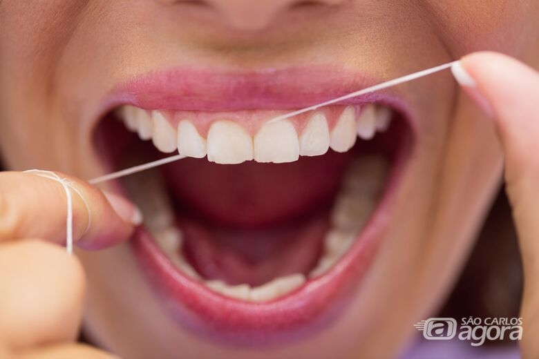 Mulher usa fio dental - Crédito: Freepik