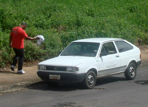 Servidor caminha em direção ao carro da prefeitura carregando faixa de protesto -