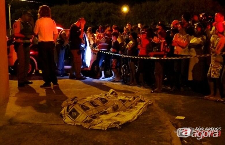 Populares observam o corpo da vítima caido na calçada. (foto: Marcio David) - 