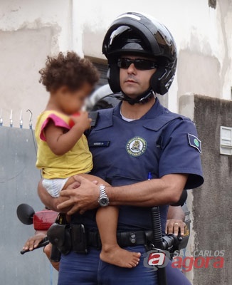 Policial segura uma das crianças que foi retirada da mãe. (foto Marcio David). -