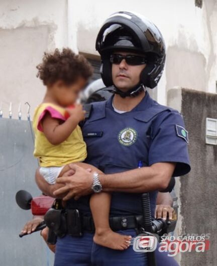 Policial segura uma das crianças que foi retirada da mãe. (foto Marcio David). - 