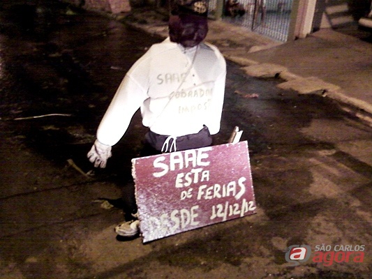 Foto mostra boneco e uma placa de protesto. -