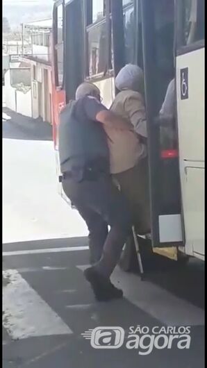 Policial militar carrega idosa com dificuldade de locomoção no colo para ajudá-la a subir no ônibus -