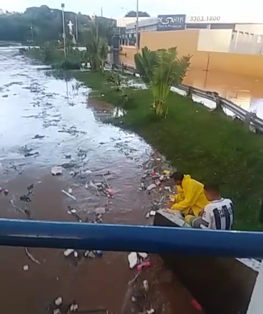 Jovens se arriscam "pescando" objetos levados pela enchente em córrego -