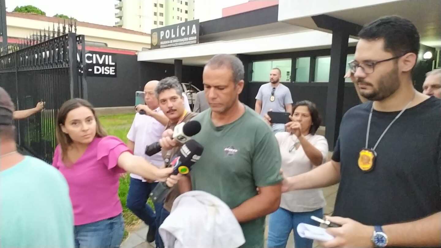 Milton, ao centro, sendo conduzido por policiais até a viatura